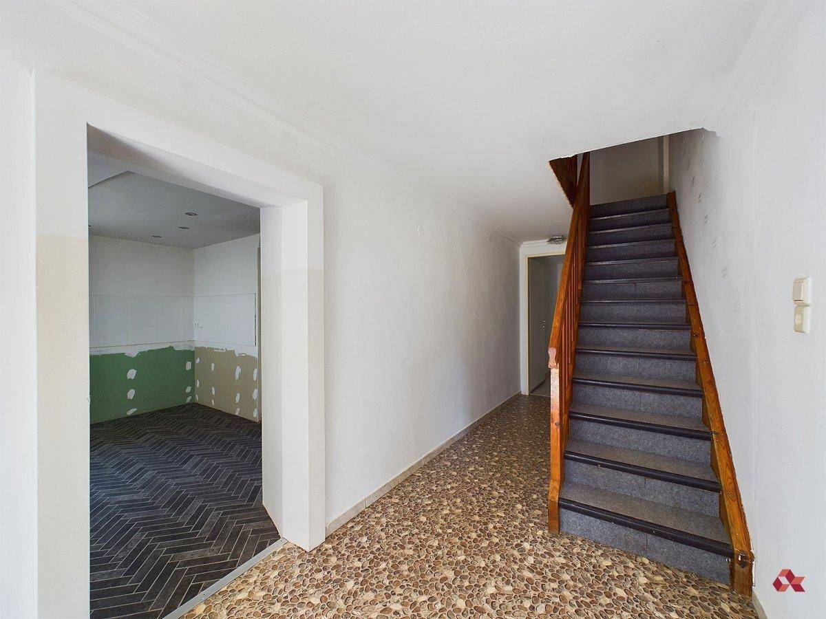 Eingangsbereich mit Treppe und Terrazzoboden, führt zu einem unfertigen Raum.