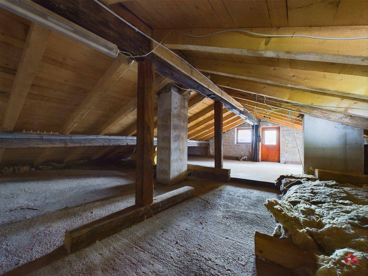 Unausgebauter Dachboden mit Holzbalken und Dämmmaterial, bereit für Renovierung.