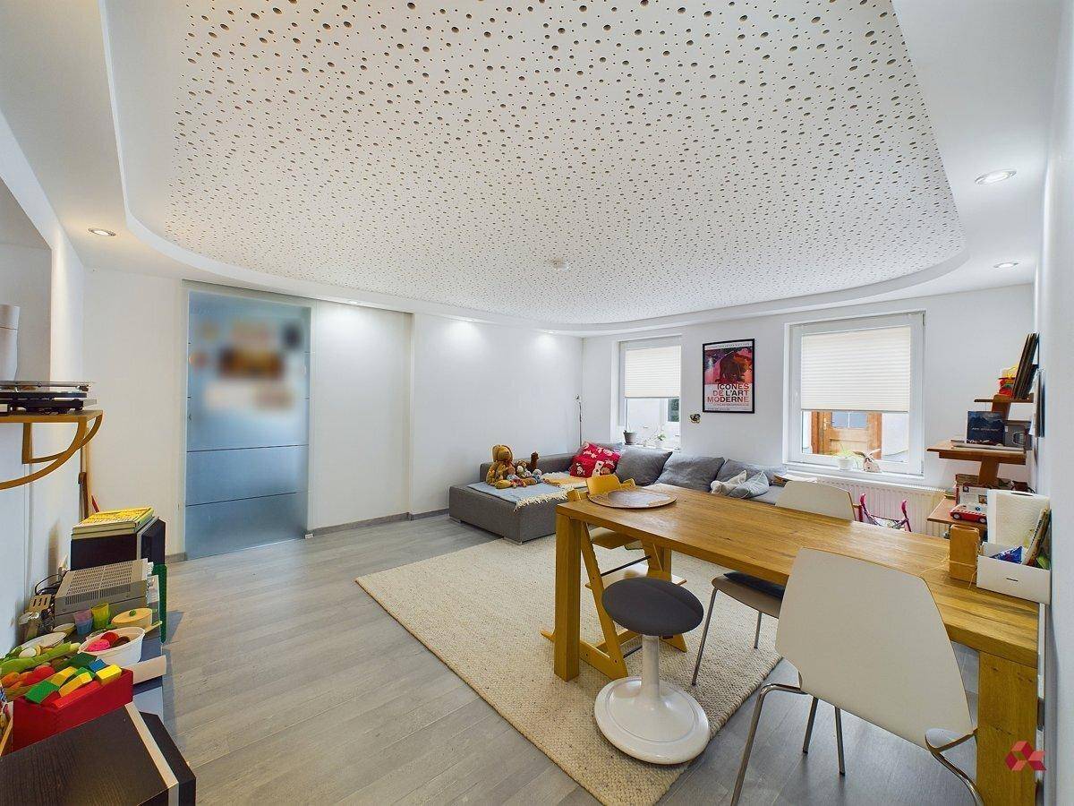 Offener Wohn- und Essbereich mit modernem Design, Holztisch und großen Fenstern.