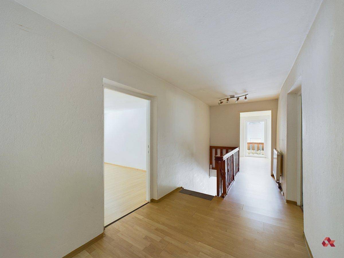 Heller Flur mit Holztreppe und Parkettboden, der zu weiteren Räumen führt.