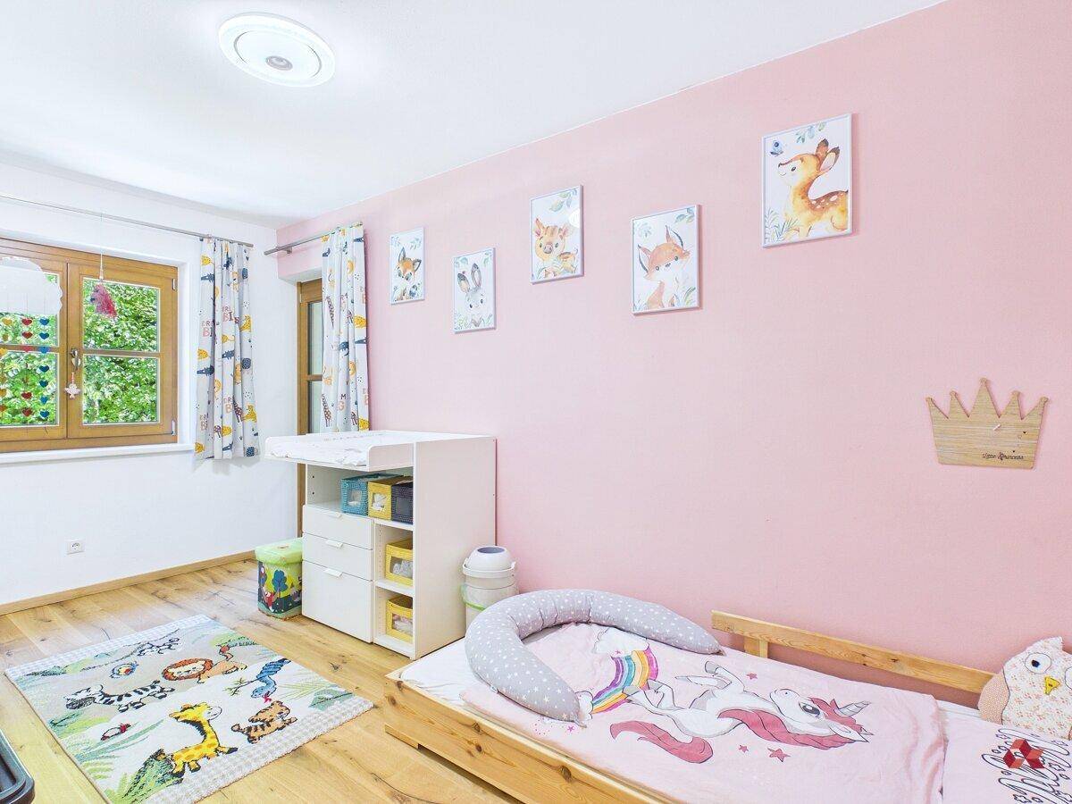 Kinderzimmer mit rosa Wänden, Holzboden und Wickeltisch, ideal für kleine Kinder.