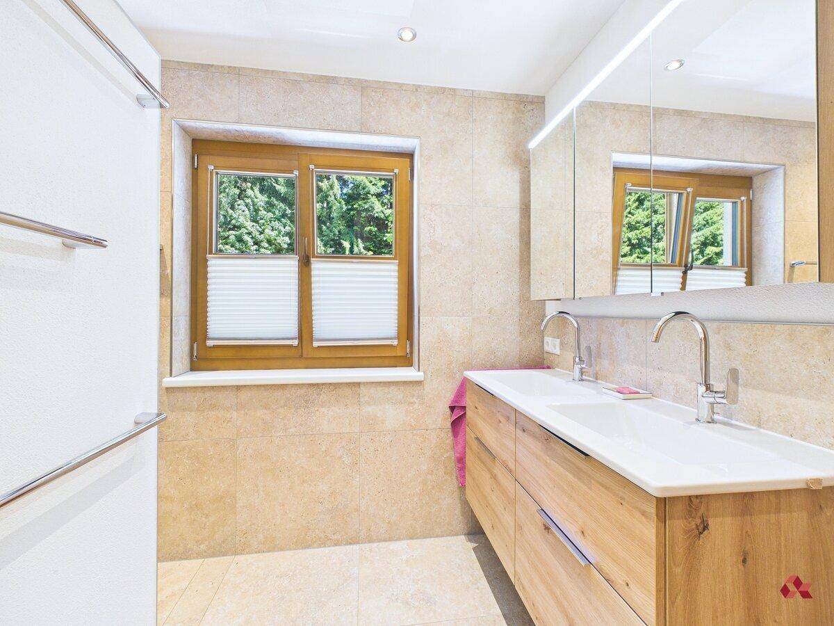 Modernes Badezimmer mit Doppelwaschbecken, Spiegelschrank und Fenster für natürliches Licht.