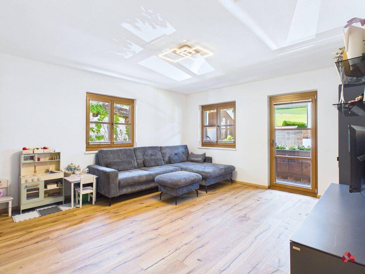 Geräumiges Wohnzimmer mit Holzboden, bequemer Couch und Blick auf die umliegende Natur.
