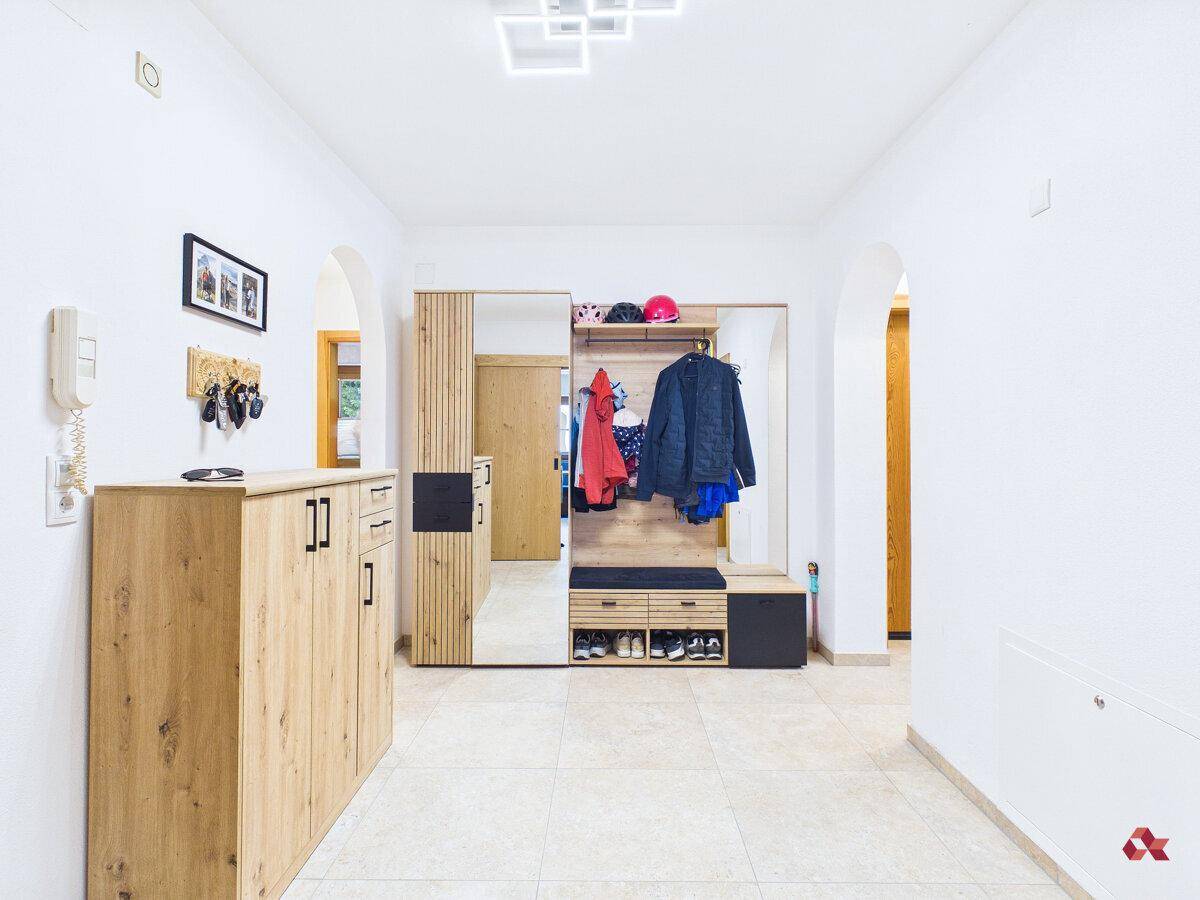 Heller Flur mit Garderobe, großem Spiegel und praktischem Schuhschrank aus Holz.