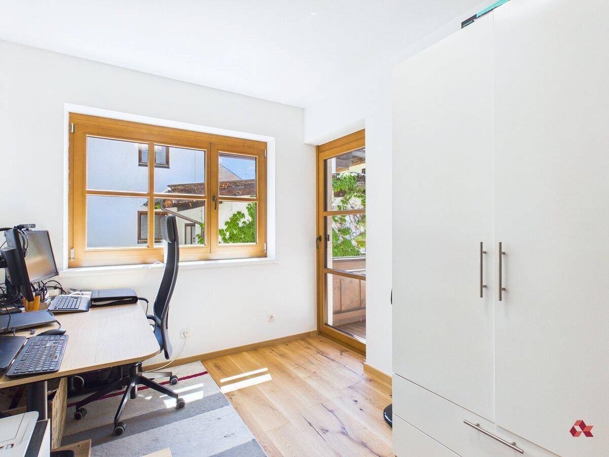 Helles Arbeitszimmer mit Schreibtisch, Bürostuhl und Fensterblick auf die Umgebung.