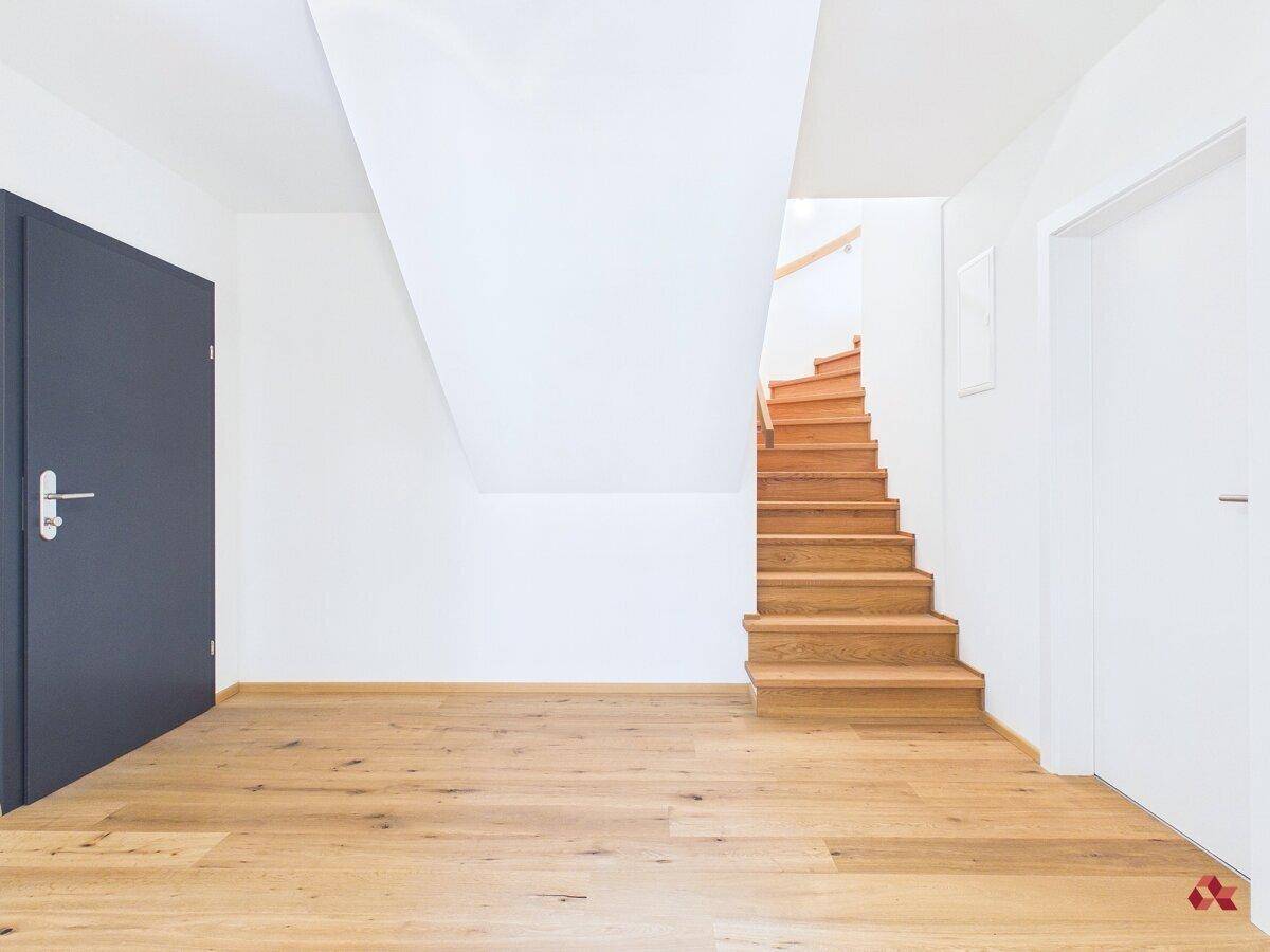 Geräumiger Eingangsbereich mit Holztreppe und hellem Parkettboden, führt in obere Etagen.