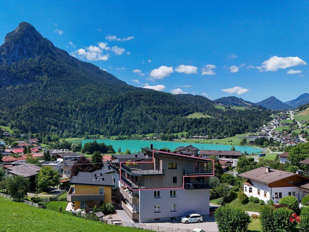 Luftaufnahme des Gebäudes mit See- und Bergblick, umgeben von grüner Landschaft.