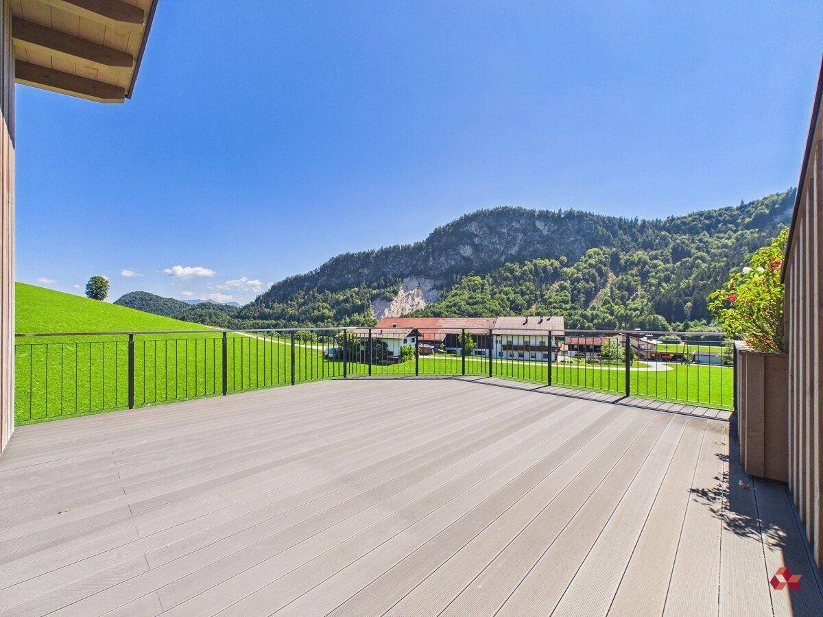 Geräumige Terrasse mit weitem Blick auf die umliegende Berglandschaft und grüne Wiesen.