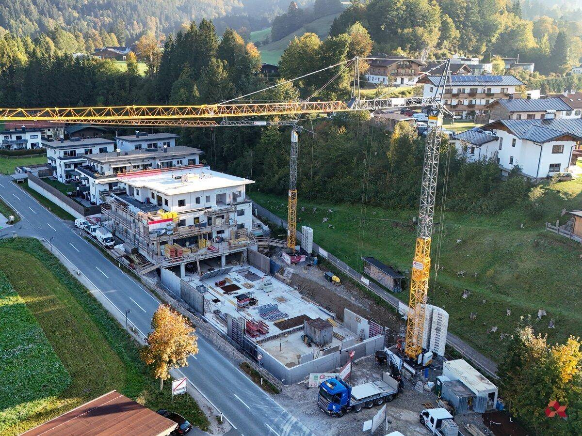 Baustelle eines neuen Wohngebäudes mit Kränen und bereits errichtetem Untergeschoss.