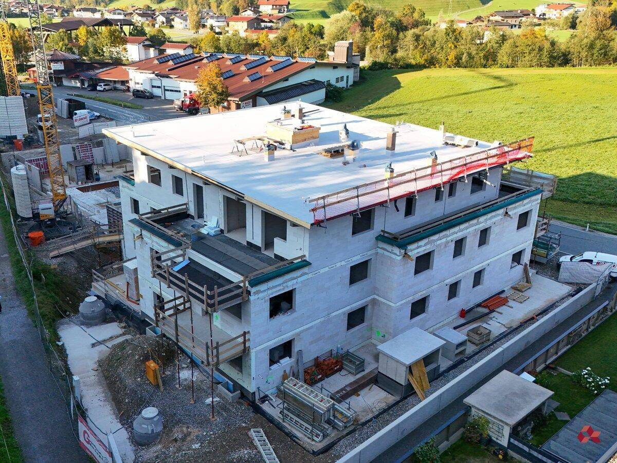 Luftaufnahme des im Bau befindlichen Gebäudes mit Rohbau und Dachkonstruktion.