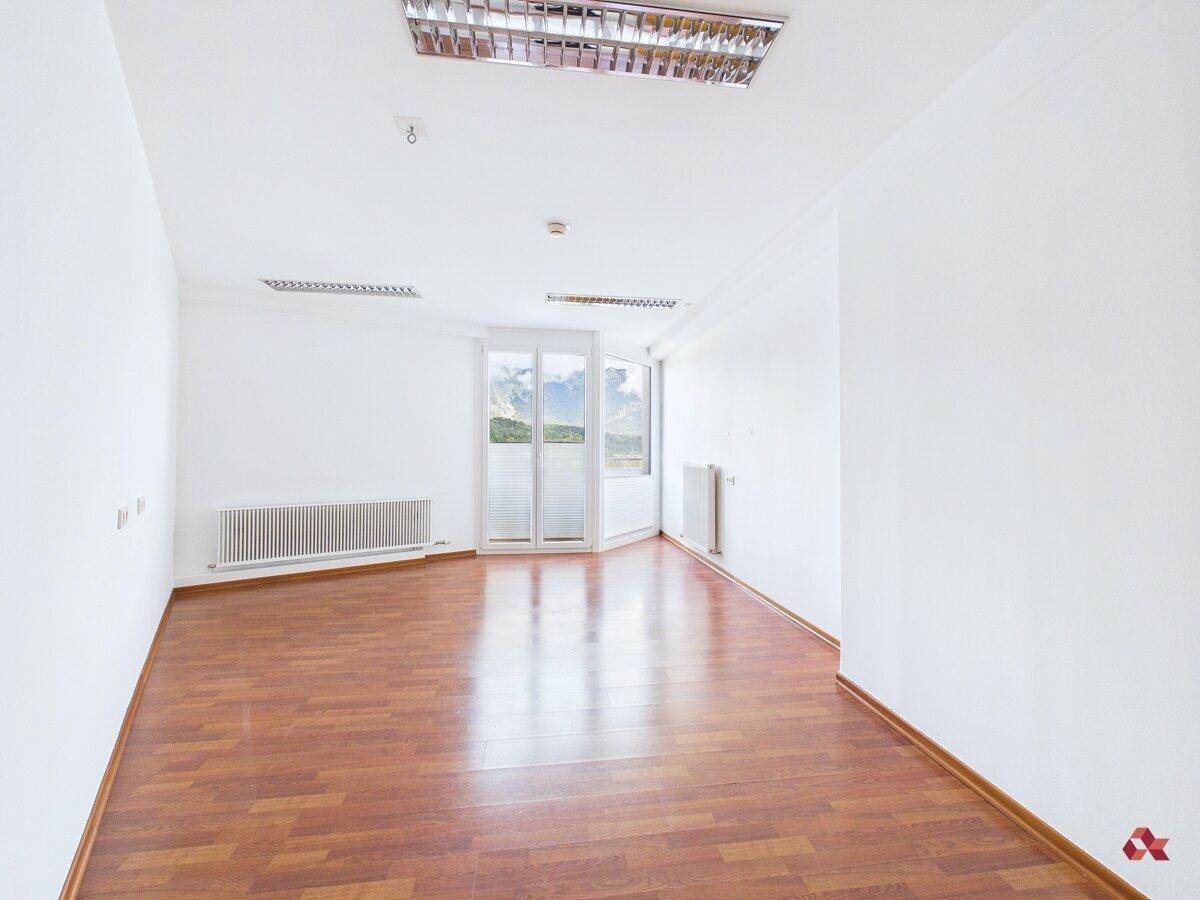 Heller Raum mit Holzboden und großen Fenstern, die viel Tageslicht hereinlassen.