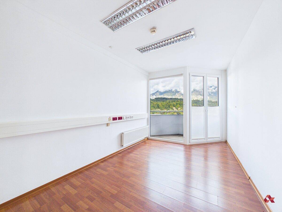 Leerer Raum mit Holzboden, Wandleisten und weitem Blick auf die umliegende Berglandschaft.