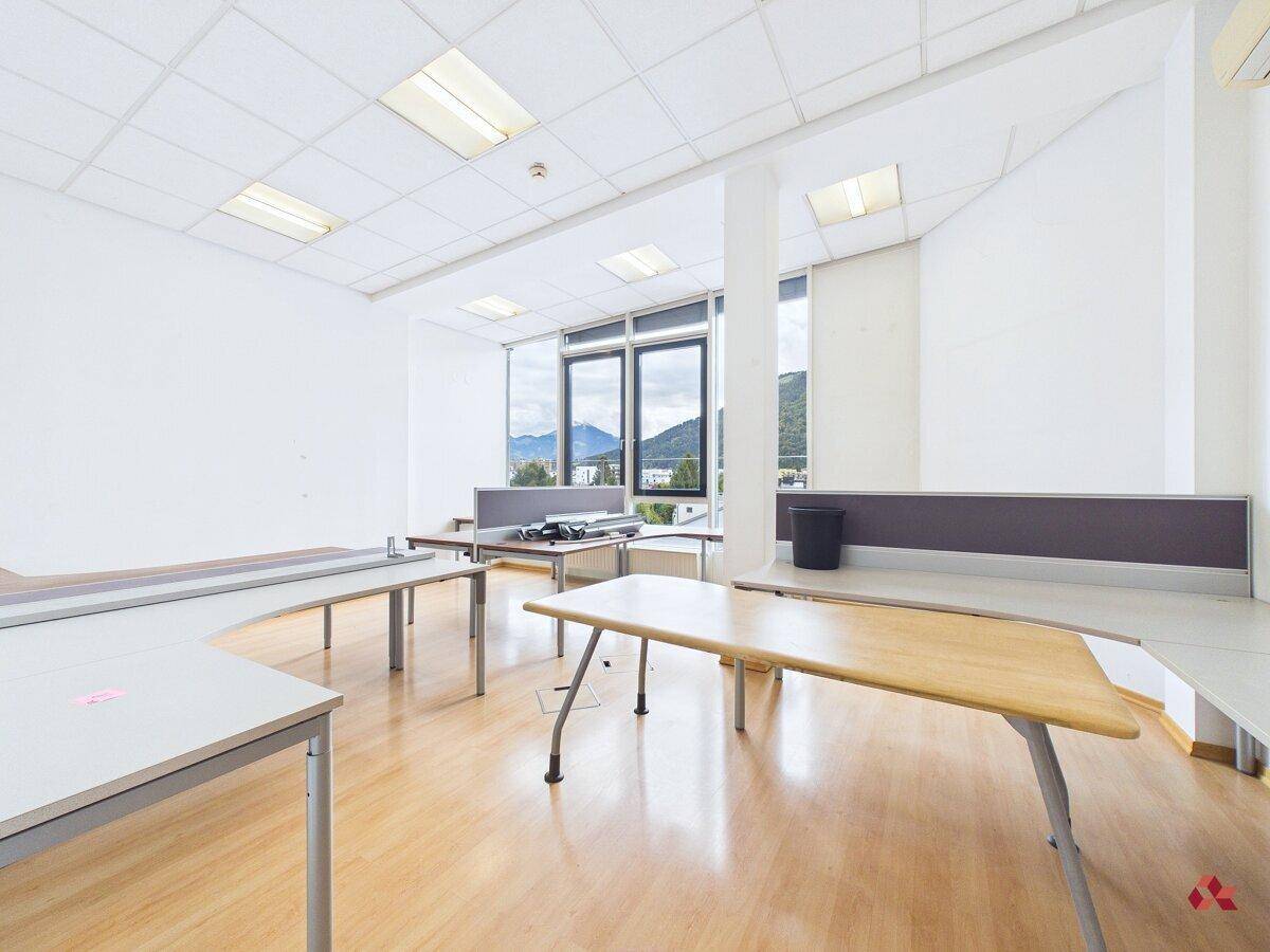 Geräumiges Büro mit mehreren Arbeitsplätzen, Holzfußboden und weitem Blick auf die Landschaft.