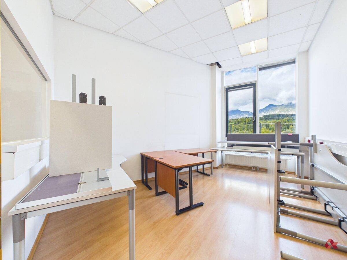 Helles Büro mit Schreibtischen, Holzfußboden und großen Fenstern mit Bergblick.