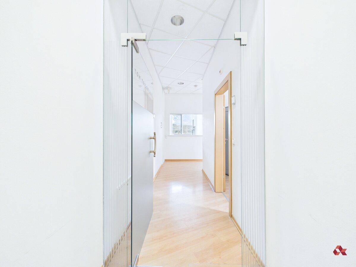 Langer, heller Flur mit Holzboden und Glastür, der zu weiteren Büroräumen führt.