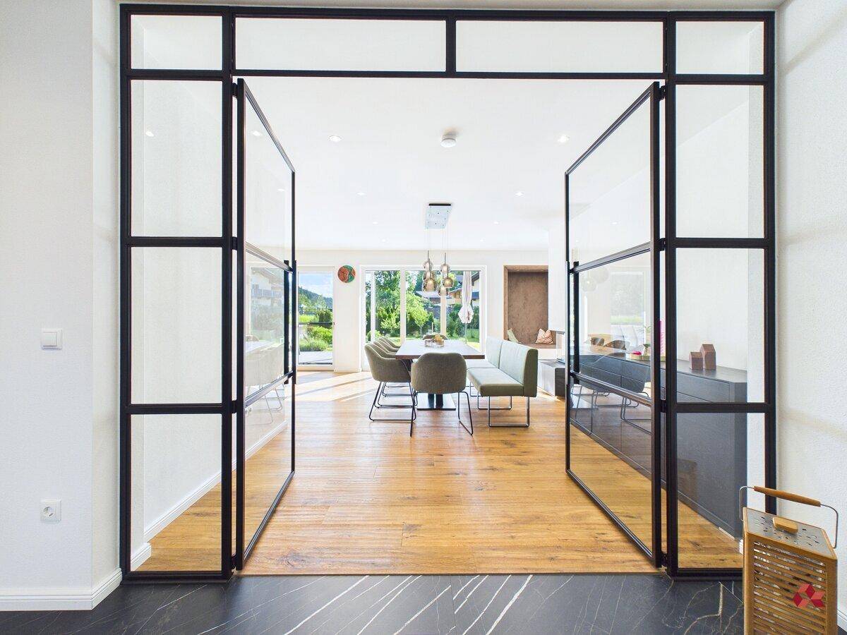 Eingangsbereich mit modernen Glastüren, dunklem Fliesenboden und Blick in den Wohnbereich.