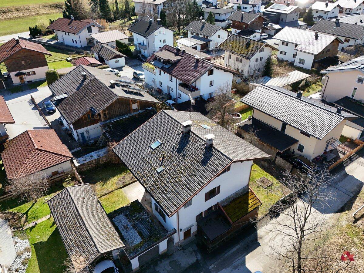 Luftaufnahme der Wohngegend mit verschiedenen Häusern und Gärten unter blauem Himmel.