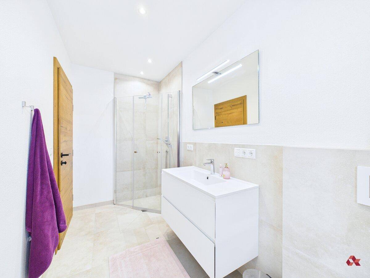 Modernes Badezimmer mit Dusche, Einzelwaschbecken und Holztür.