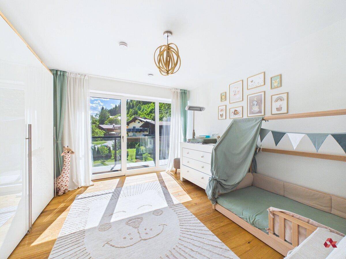 Helles Kinderzimmer mit Holzboden, Spielbereich und Zugang zum Balkon.