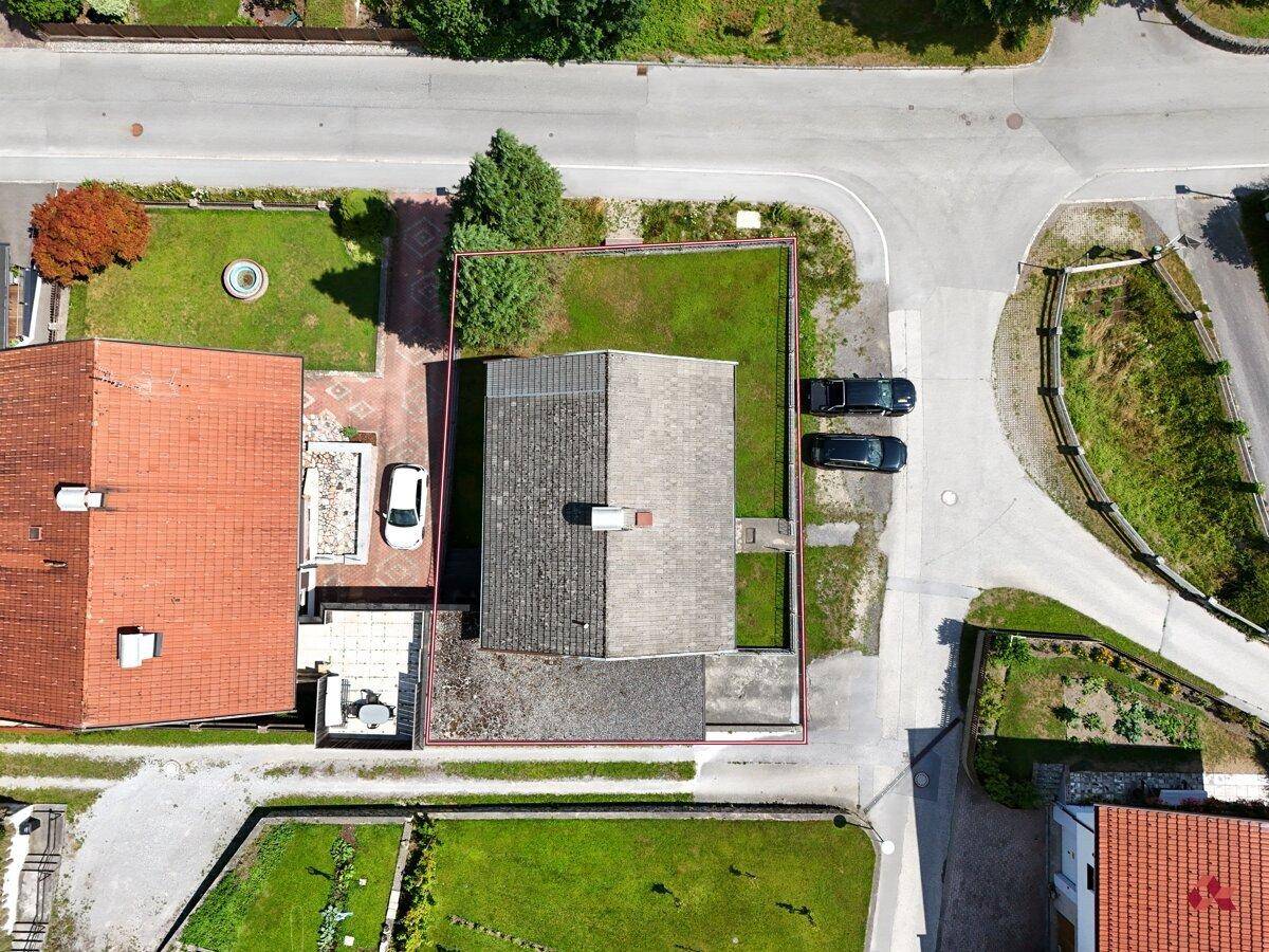 Senkrechte Luftaufnahme des Grundstücks mit Haus, Garten, angrenzender Straße und Parkplätzen.