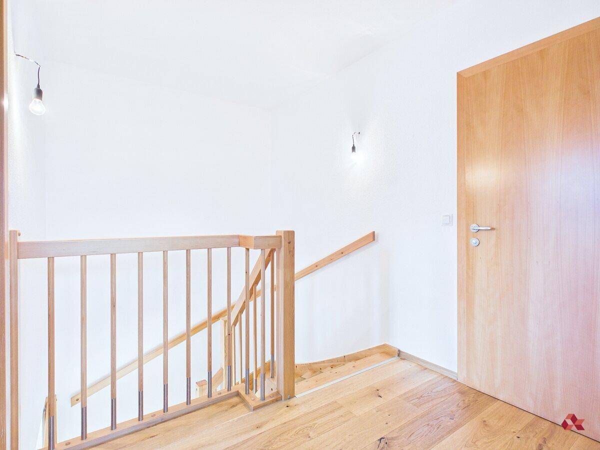 Heller Treppenaufgang mit Holzgeländer und Holzboden führt in die obere Etage.