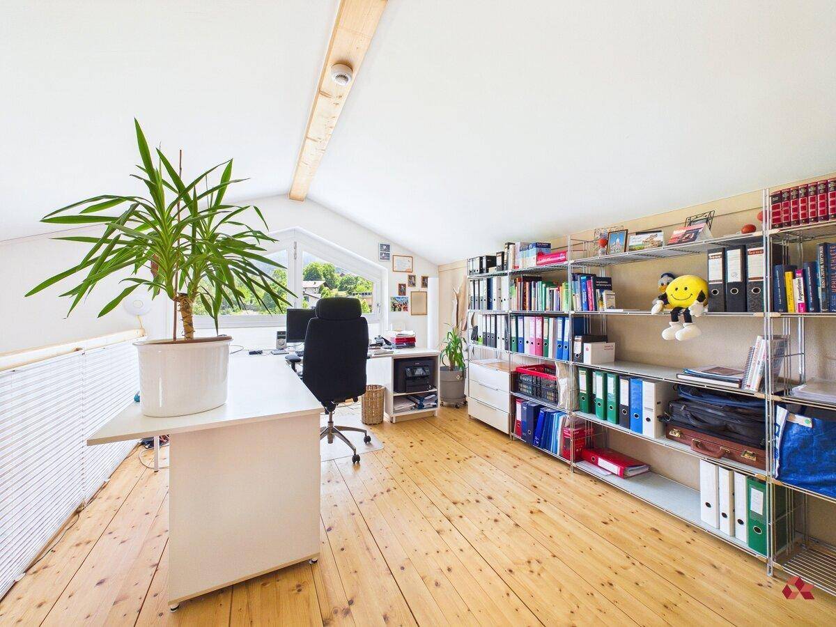 Helles Büro im Dachgeschoss mit Holzfußboden, Dachschräge und Blick ins Grüne.