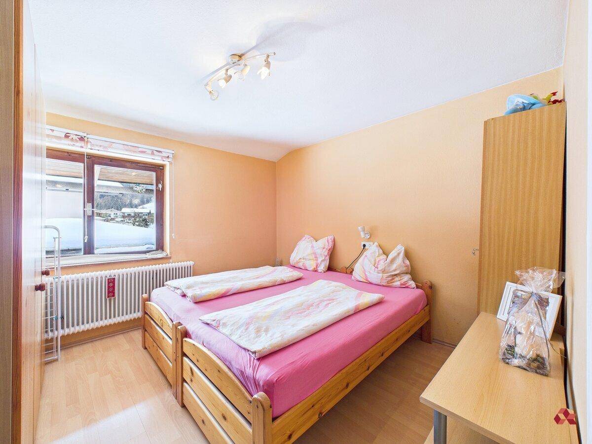 Freundliches Schlafzimmer mit zwei Einzelbetten und Blick auf die verschneite Landschaft.