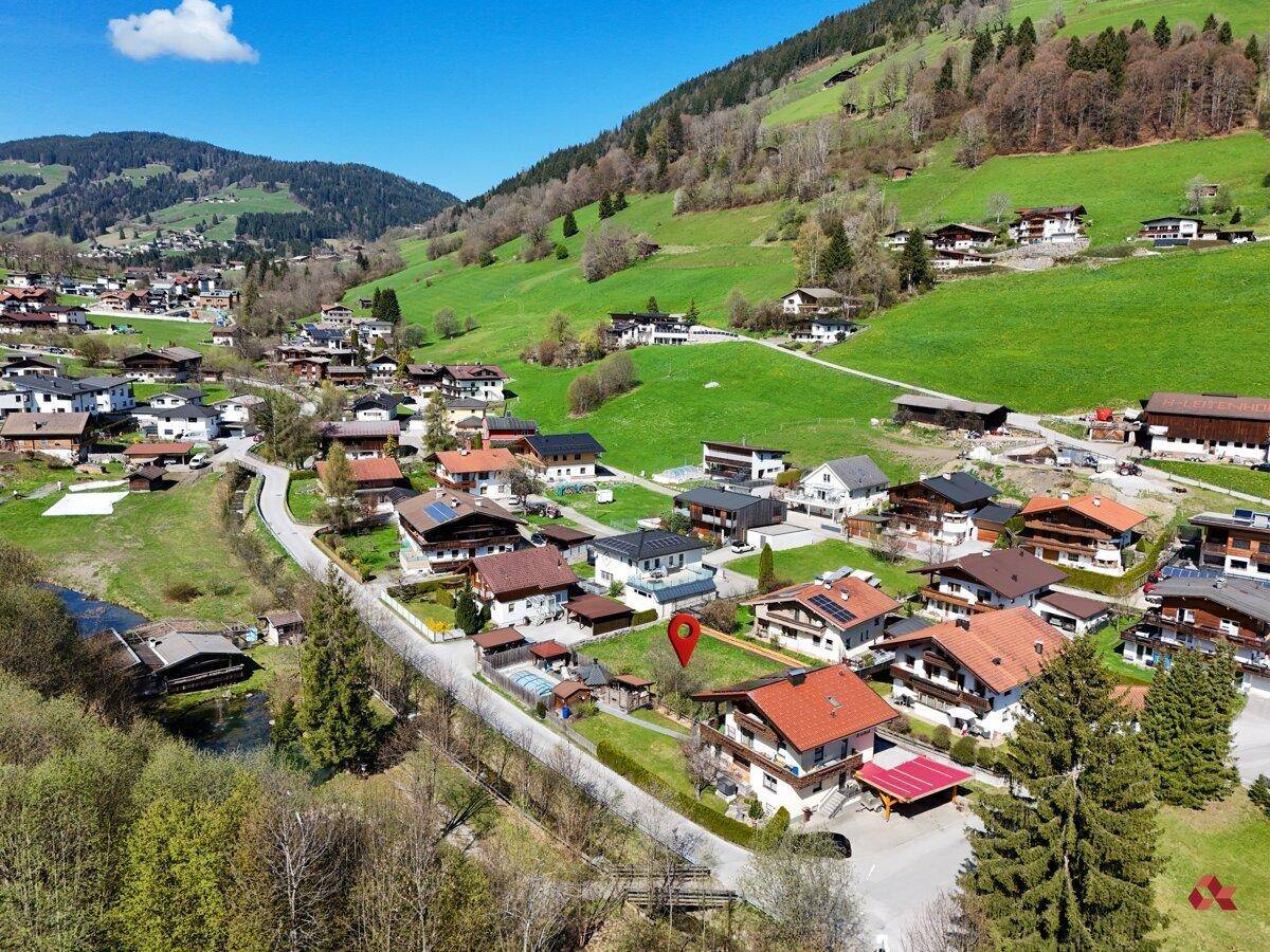 Panoramische Luftaufnahme eines malerischen Dorfes eingebettet in eine grüne Berglandschaft.