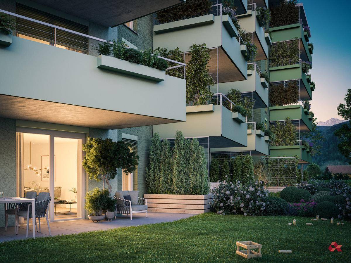 Ruhige Gartenterrasse mit Sitzgelegenheiten und gepflegtem Rasen vor der grünen Gebäudefassade.
