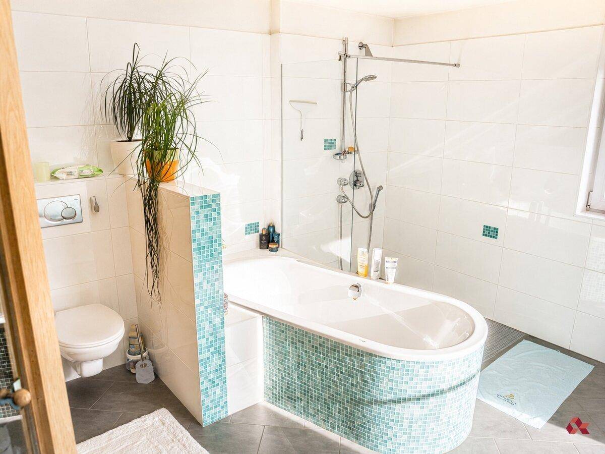 Helles Badezimmer mit Badewanne, Dusche, WC und farbigen Mosaikfliesen.