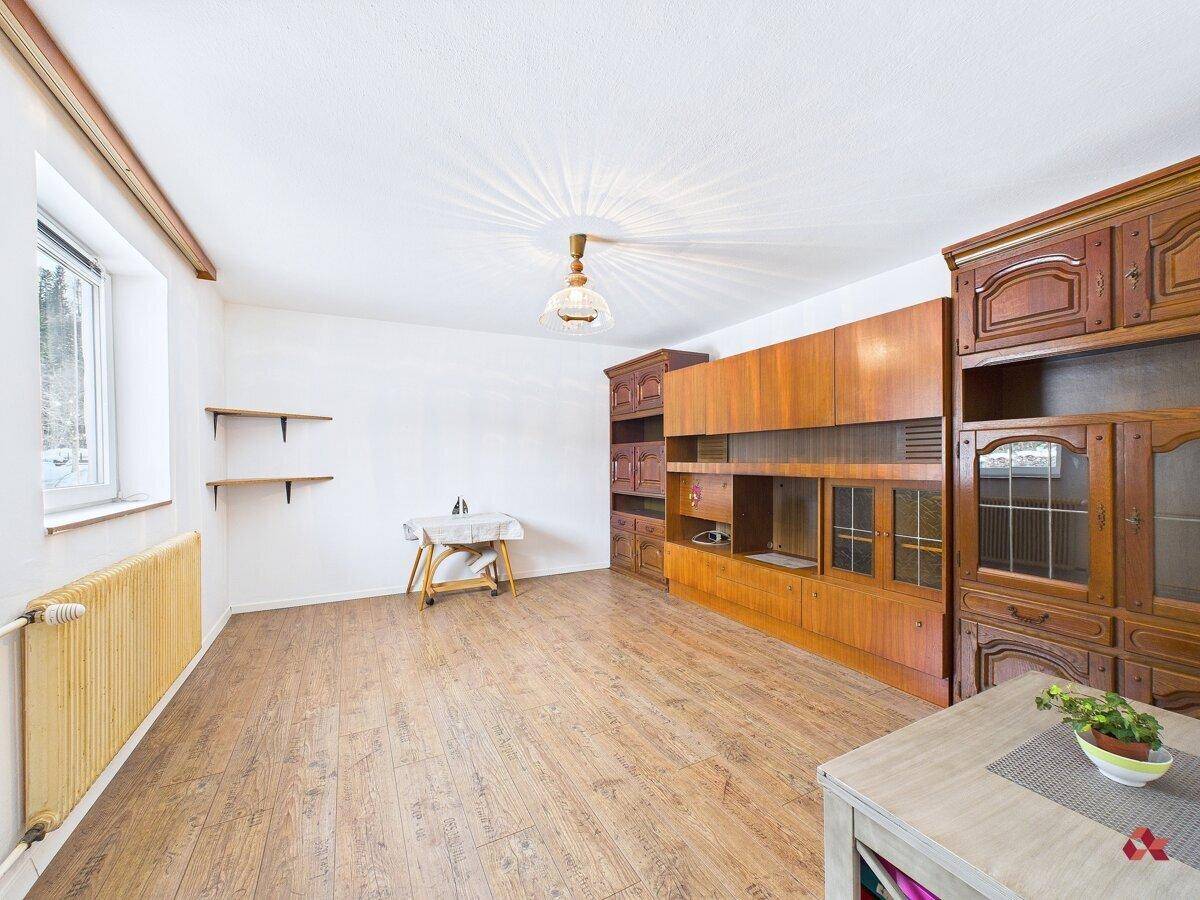 Geräumiges Wohnzimmer mit Holzschrankwand und Laminatboden, bereit zur individuellen Gestaltung.