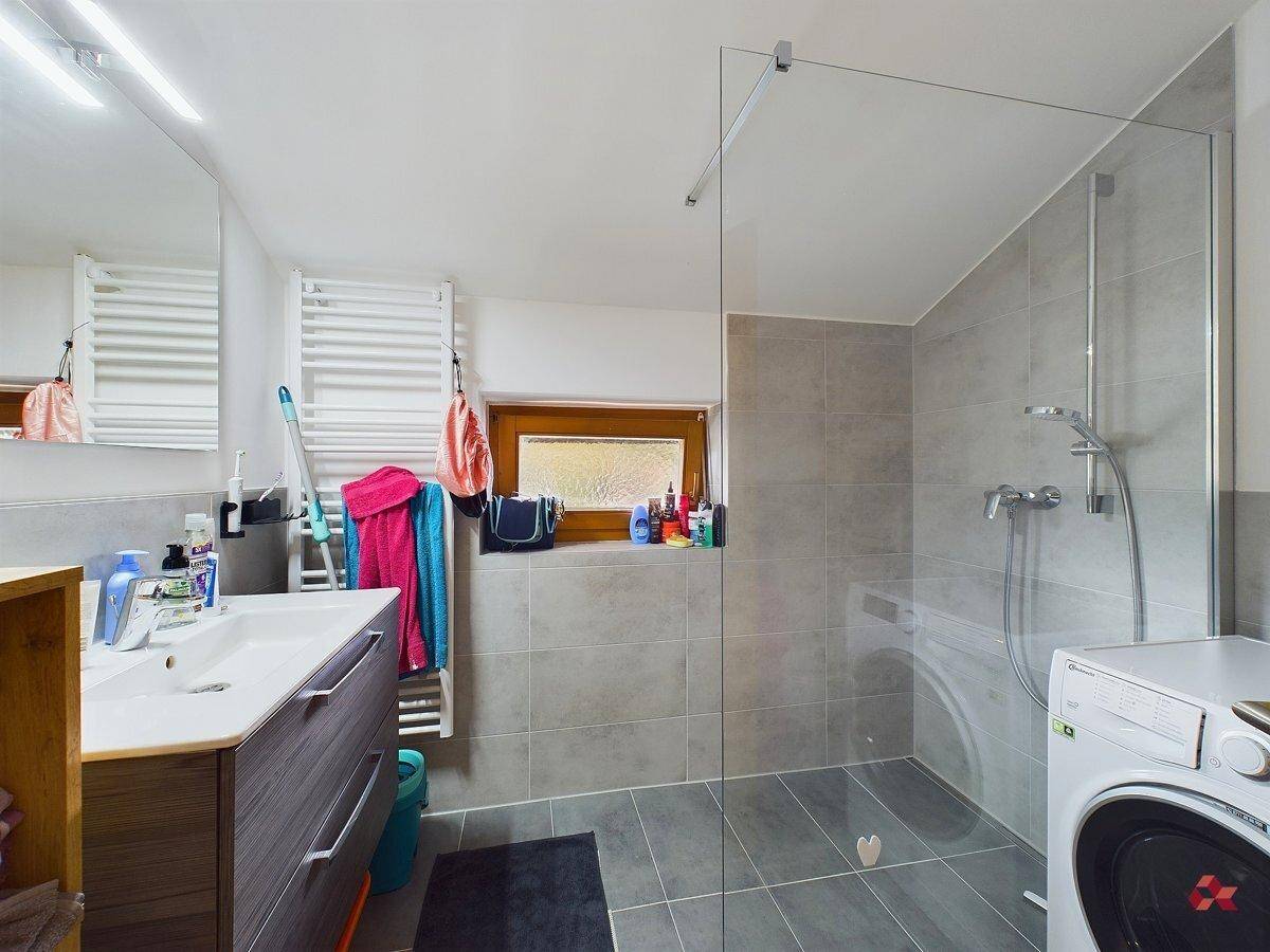 Modernes Badezimmer mit ebenerdiger Dusche, Waschbecken und beheiztem Handtuchhalter.