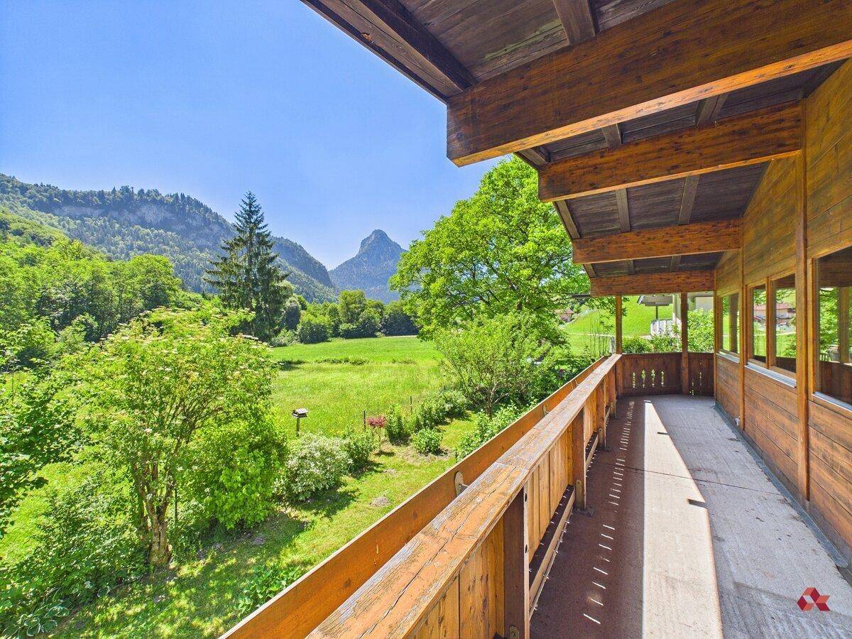 Geräumiger Holzbalkon mit weitem Blick über grüne Wiesen und majestätische Berge.