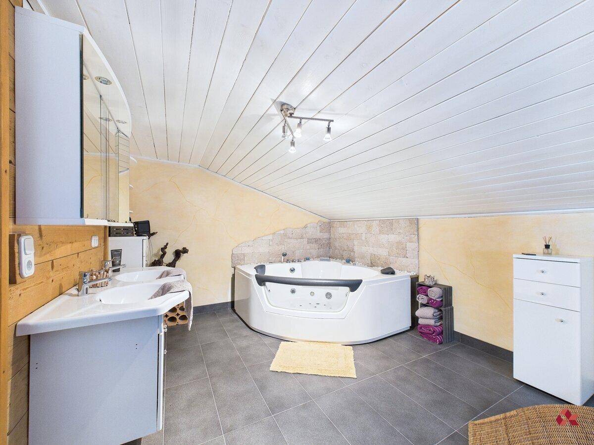 Geräumiges Badezimmer im Dachgeschoss mit Whirlpool, Doppelwaschbecken und Holzakzenten.