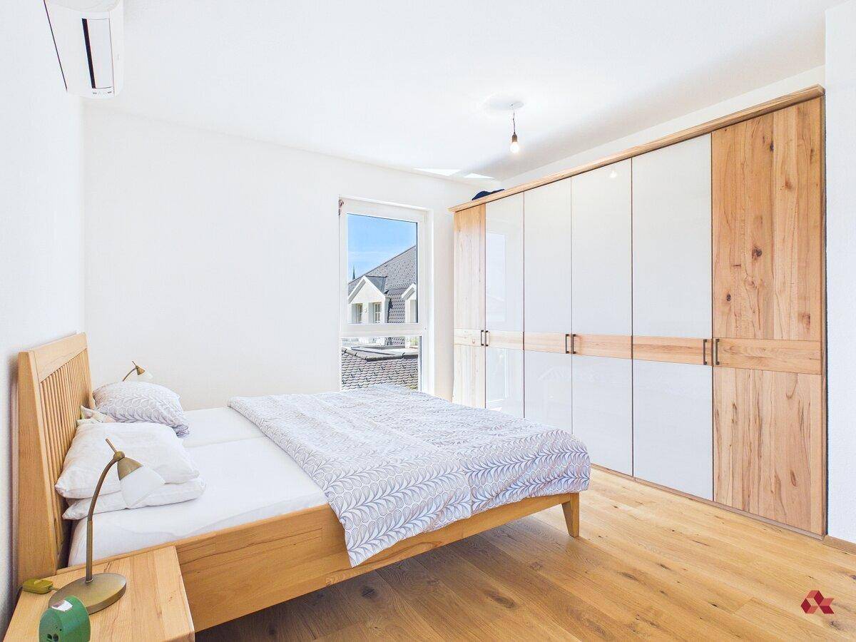 Schlafzimmer mit großem Einbauschrank, Holzboden und viel Tageslicht.