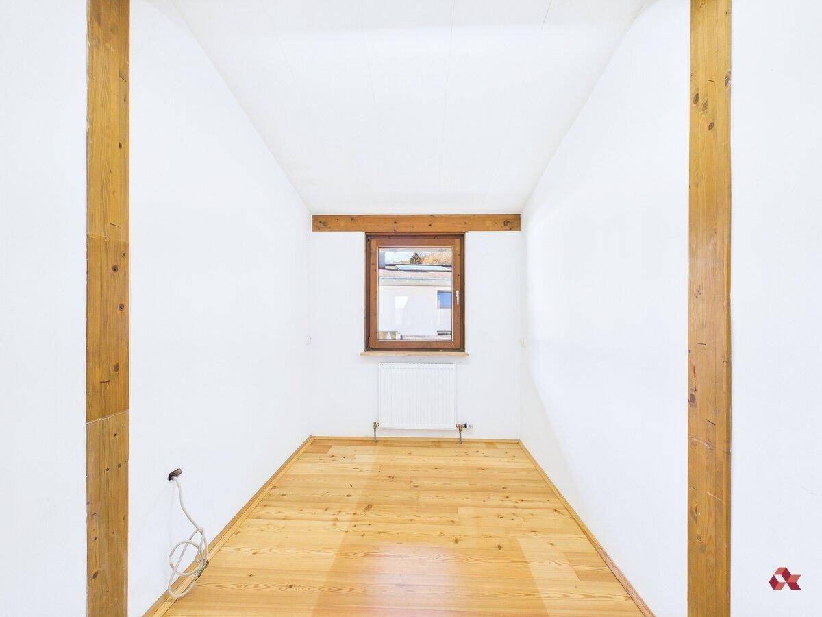 Gemütliches Schlafzimmer mit Holzbalken, Parkettboden und Fenster, bietet rustikalen Charme.