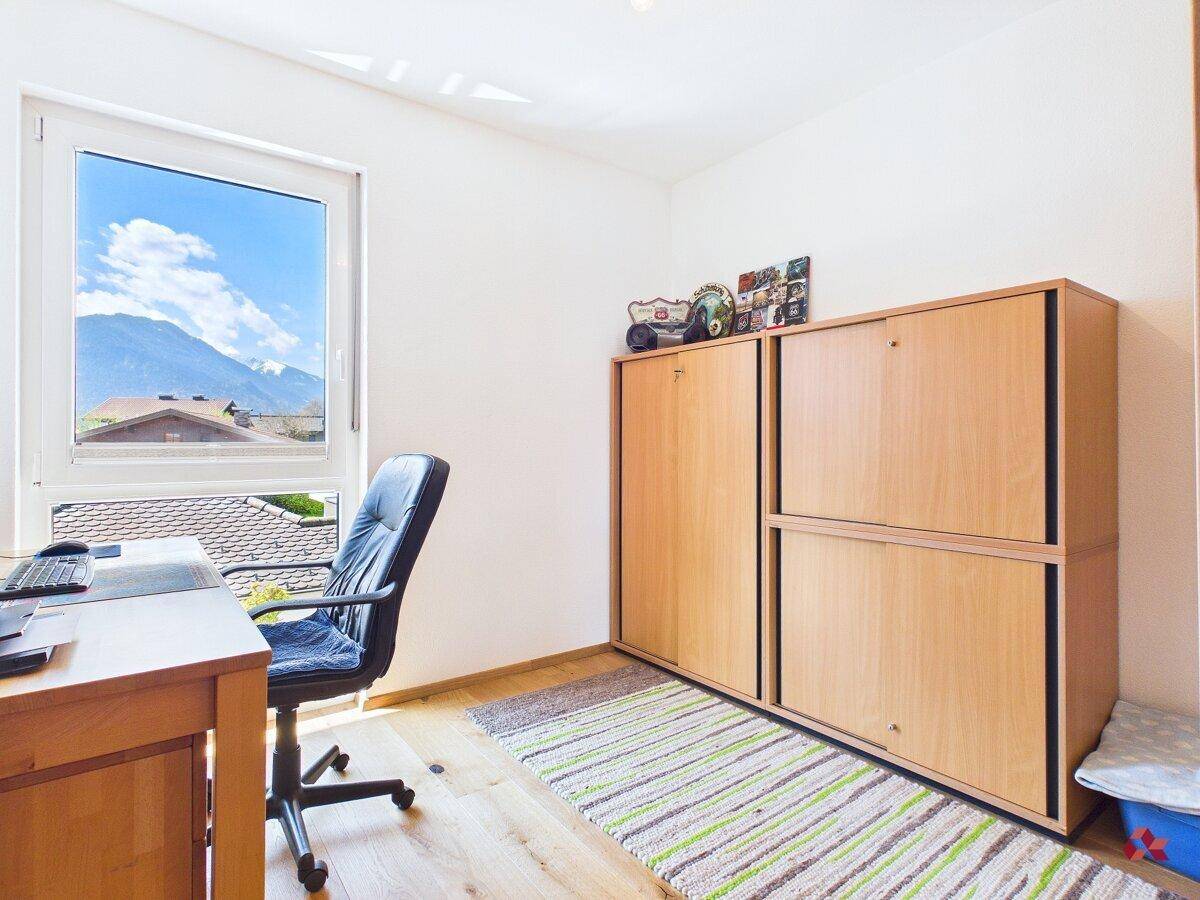 Arbeitszimmer mit Schreibtisch, Holzschränken und Bergblick aus dem Fenster.