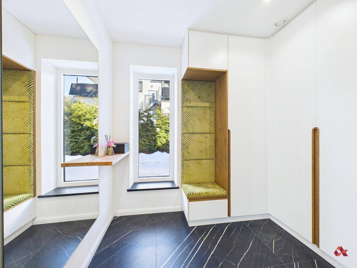 Eingangsbereich mit Einbauschränken, Sitzbank und Fenster mit Blick nach draußen.