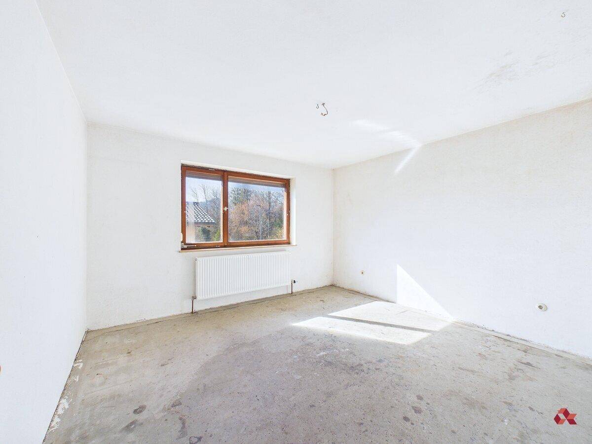 Heller Raum mit Betonboden, weiß gestrichenen Wänden und einem Fenster.