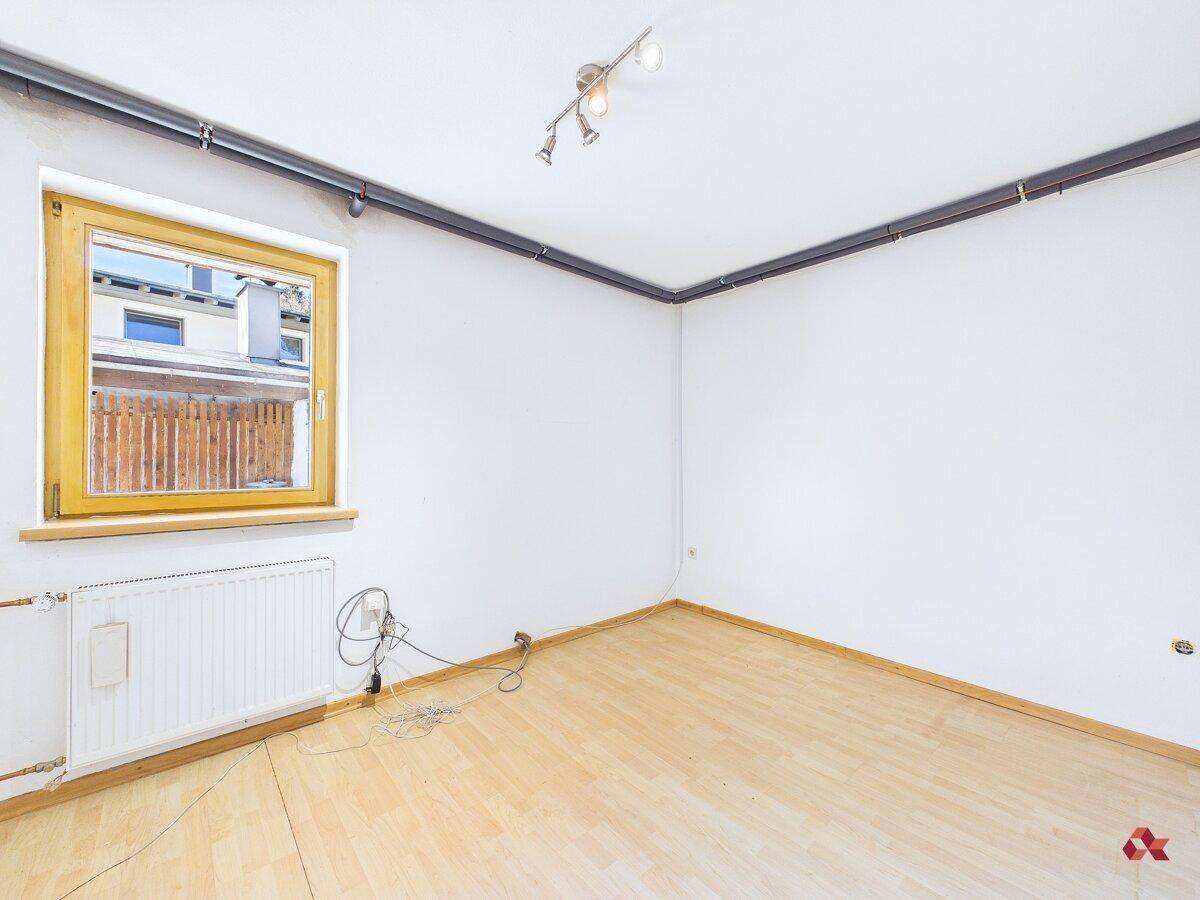 Heller Raum mit Laminatboden, Heizkörper und Fenster, bereit zur individuellen Gestaltung.
