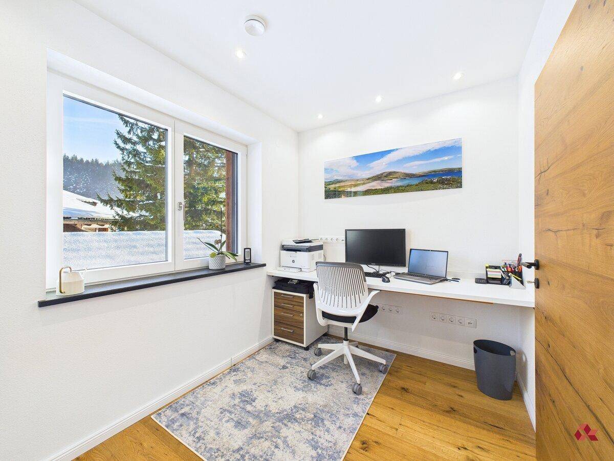 Helles Büro mit Holzboden, großem Fenster und Blick auf die verschneite Landschaft.