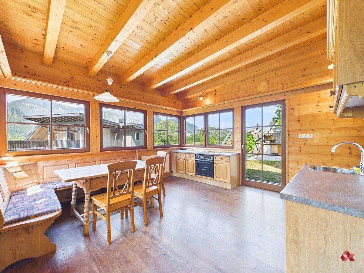 Gemütliche Wohnküche im Landhausstil mit viel Holz, Essbereich und Blick ins Grüne.