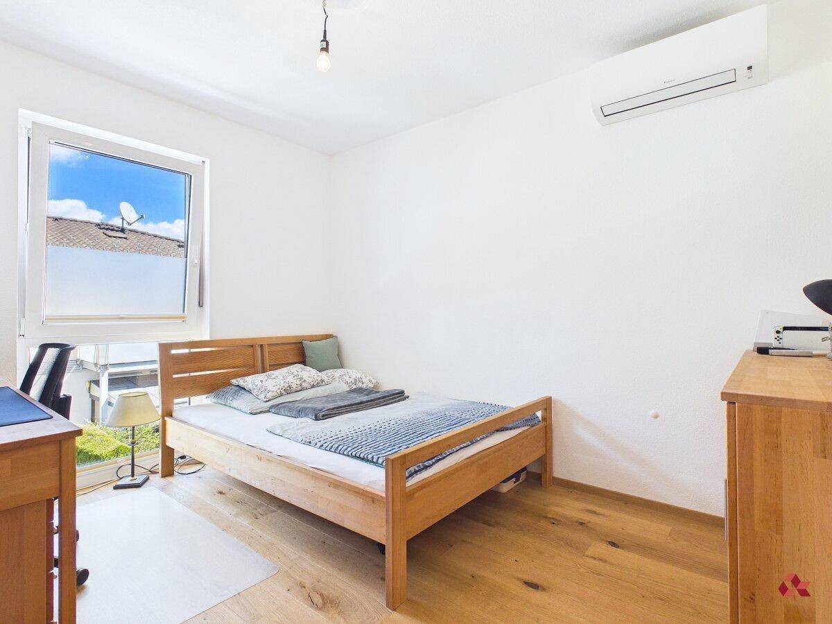 Helles Schlafzimmer mit Holzbett, Parkettboden und Klimaanlage.