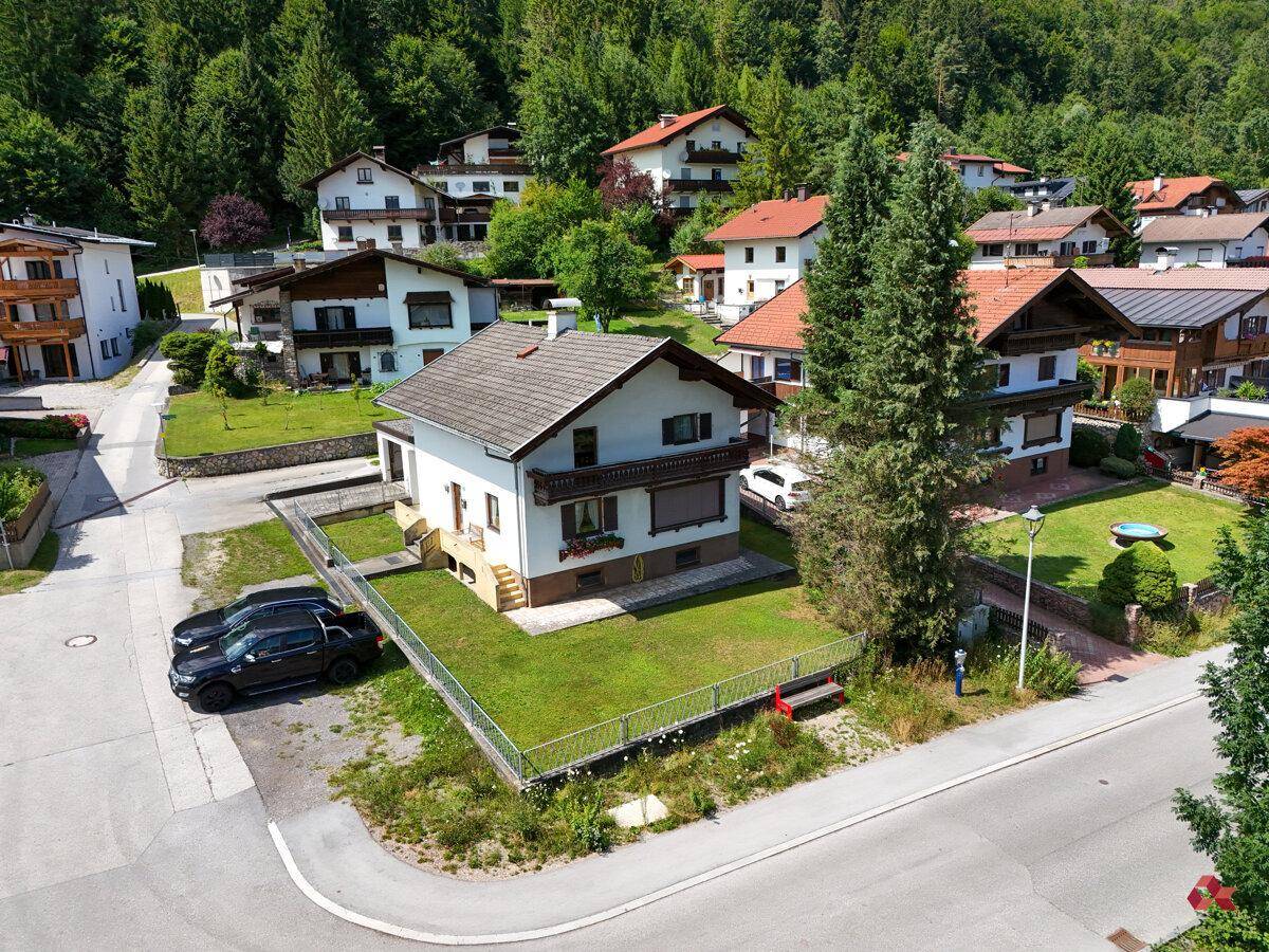 Vogelperspektive eines Einfamilienhauses mit Garten, angrenzender Straße und weiteren Gebäuden in ländlicher Umgebung.