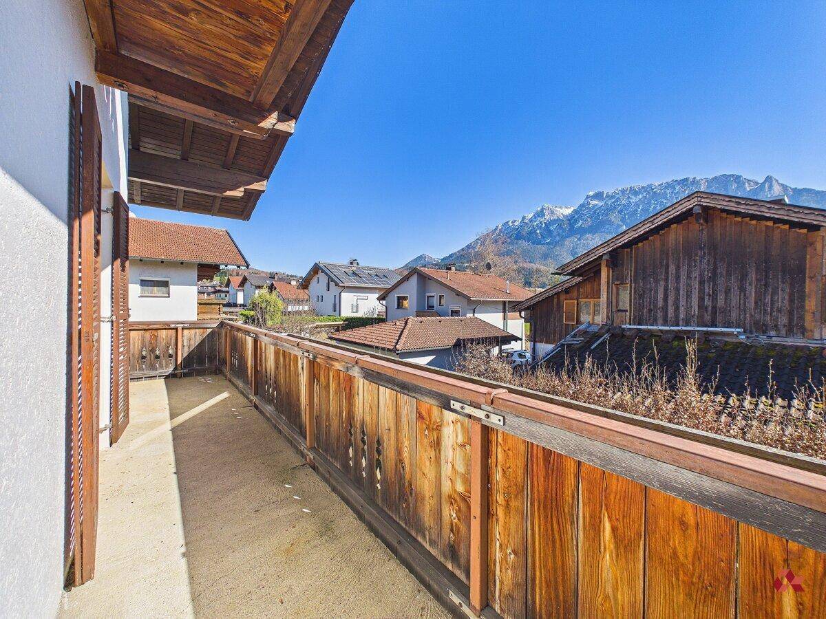 Balkon mit Holzelementen und weitem Blick auf die Berge und die Nachbarschaft.