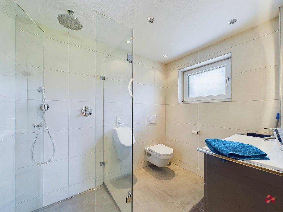 Modernes Badezimmer mit begehbarer Dusche, wandhängendem WC und Urinal.