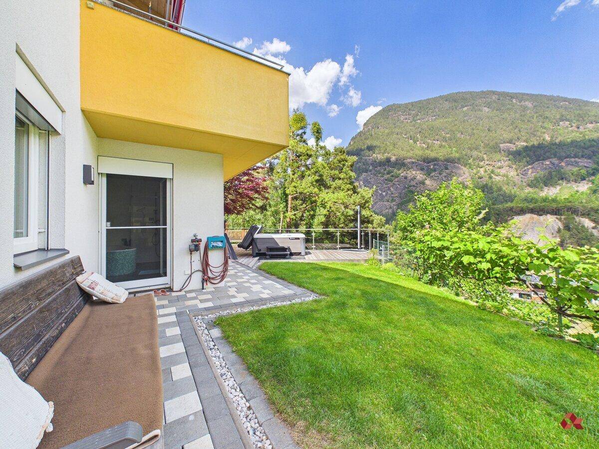 Schöner Garten mit Rasenfläche, Sitzbank und Zugang zur Terrasse mit Whirlpool.