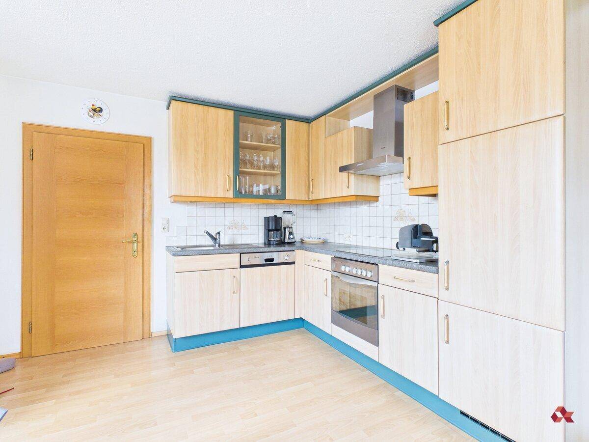 Helle Küche mit hellen Holzfronten, blauen Akzenten und integrierten Geräten.