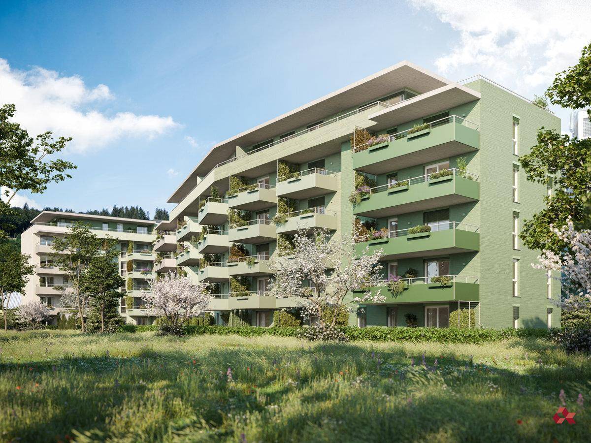 Moderne Wohnanlage mit grüner Fassade, Balkonen und blühenden Bäumen in ländlicher Umgebung.