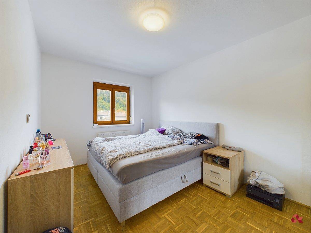 Gemütliches Schlafzimmer mit Doppelbett, Parkettboden und Fenster mit Blick ins Grüne.